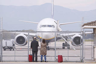Uns viatgers contemplen un avió estacionat a l'aeroport de Girona-Costa Brava. <br/>